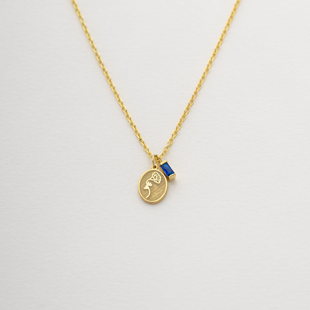 Gold necklace with a pendant on a light gray background