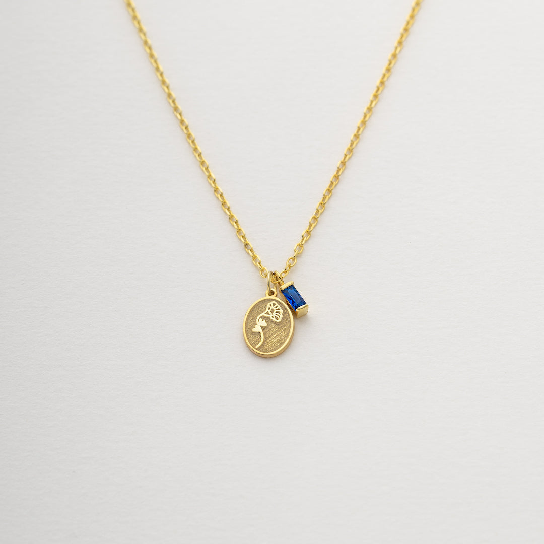 Gold necklace with a pendant on a light gray background