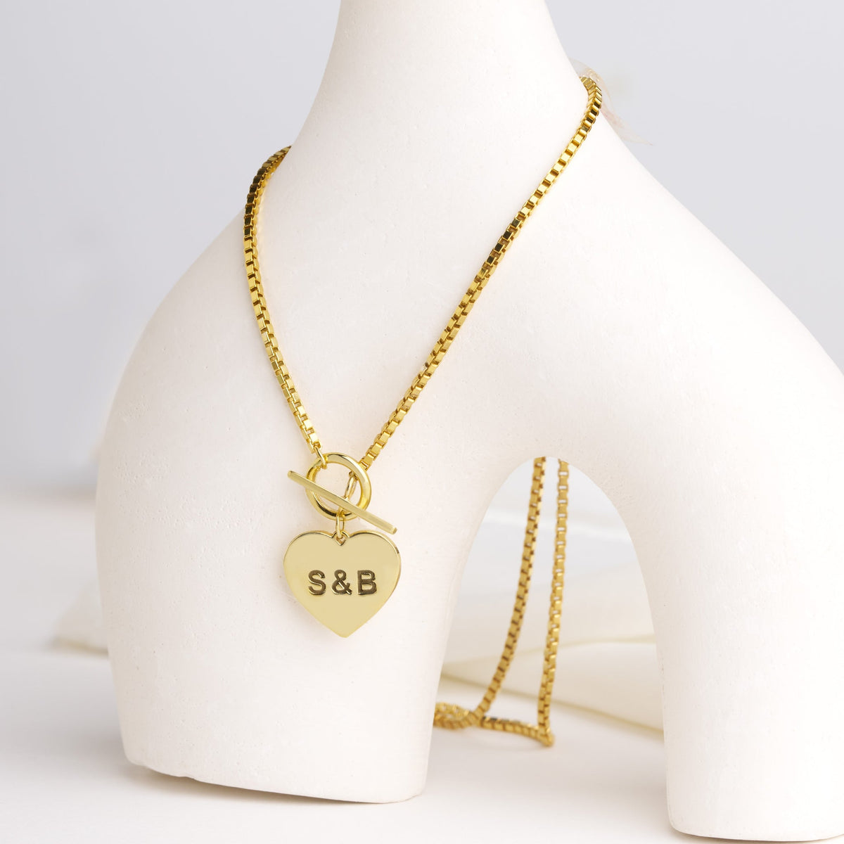 Custom engraved heart toggle necklace laid flat on a light background