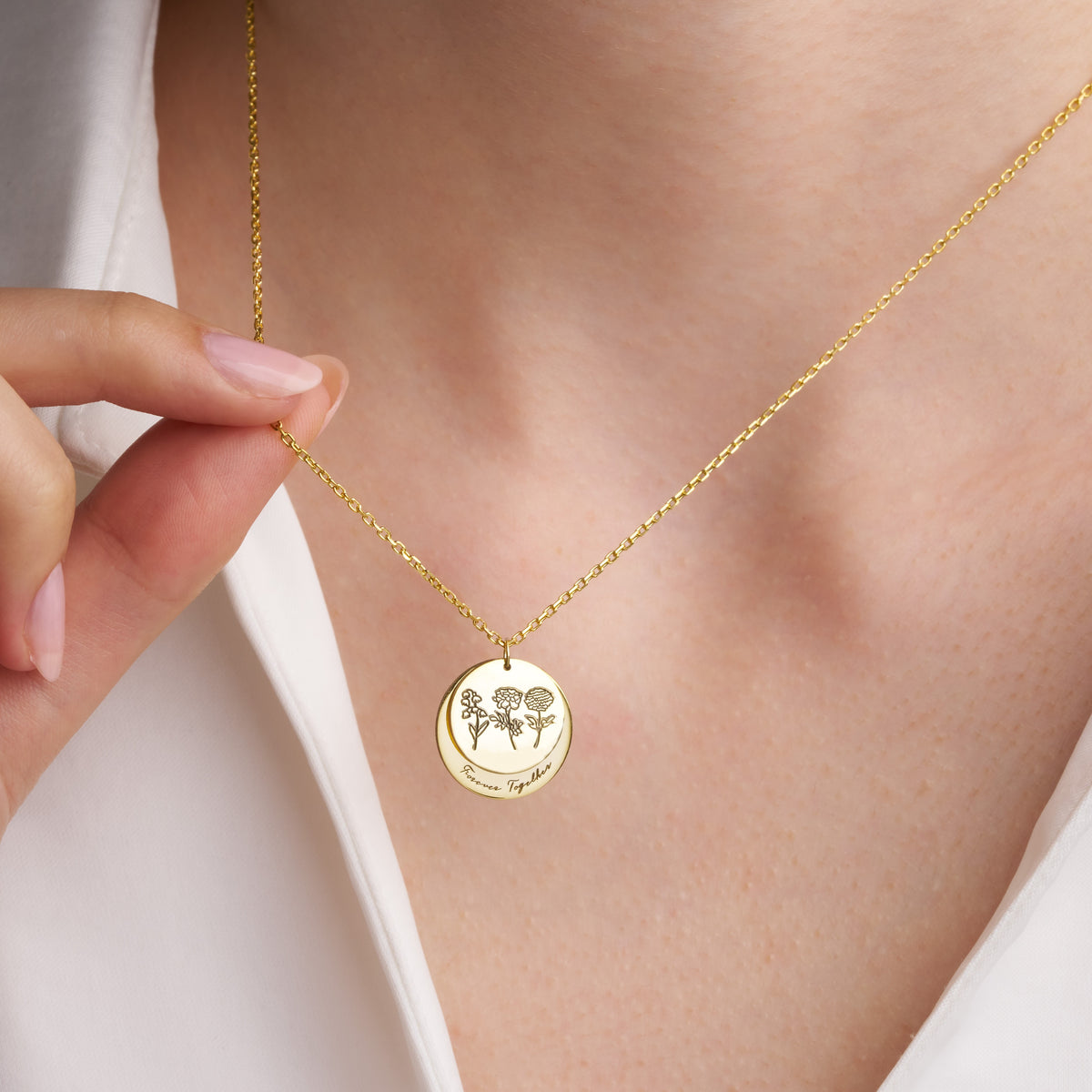 Close-up of the engraved birth flower discs worn on the neck