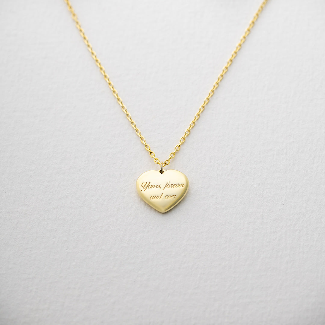 Gold heart-shaped pendant necklace on a light gray background