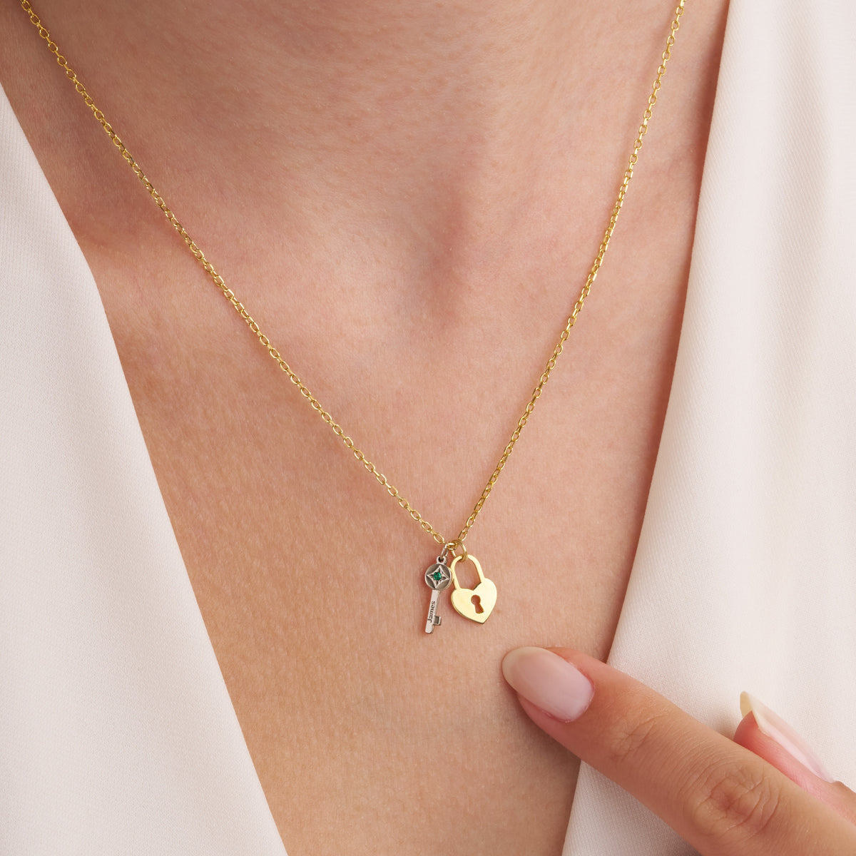 Close-up of the silver birthstone key and gold heart lock pendants worn on the neck