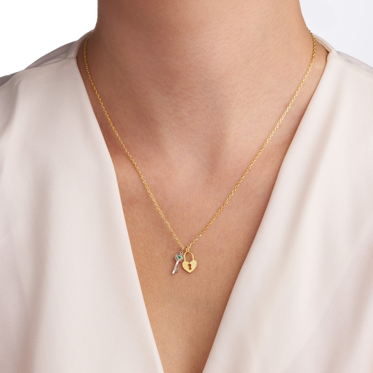 Key and heart lock birthstone necklace worn at the collarbone with a cream V-neck top
