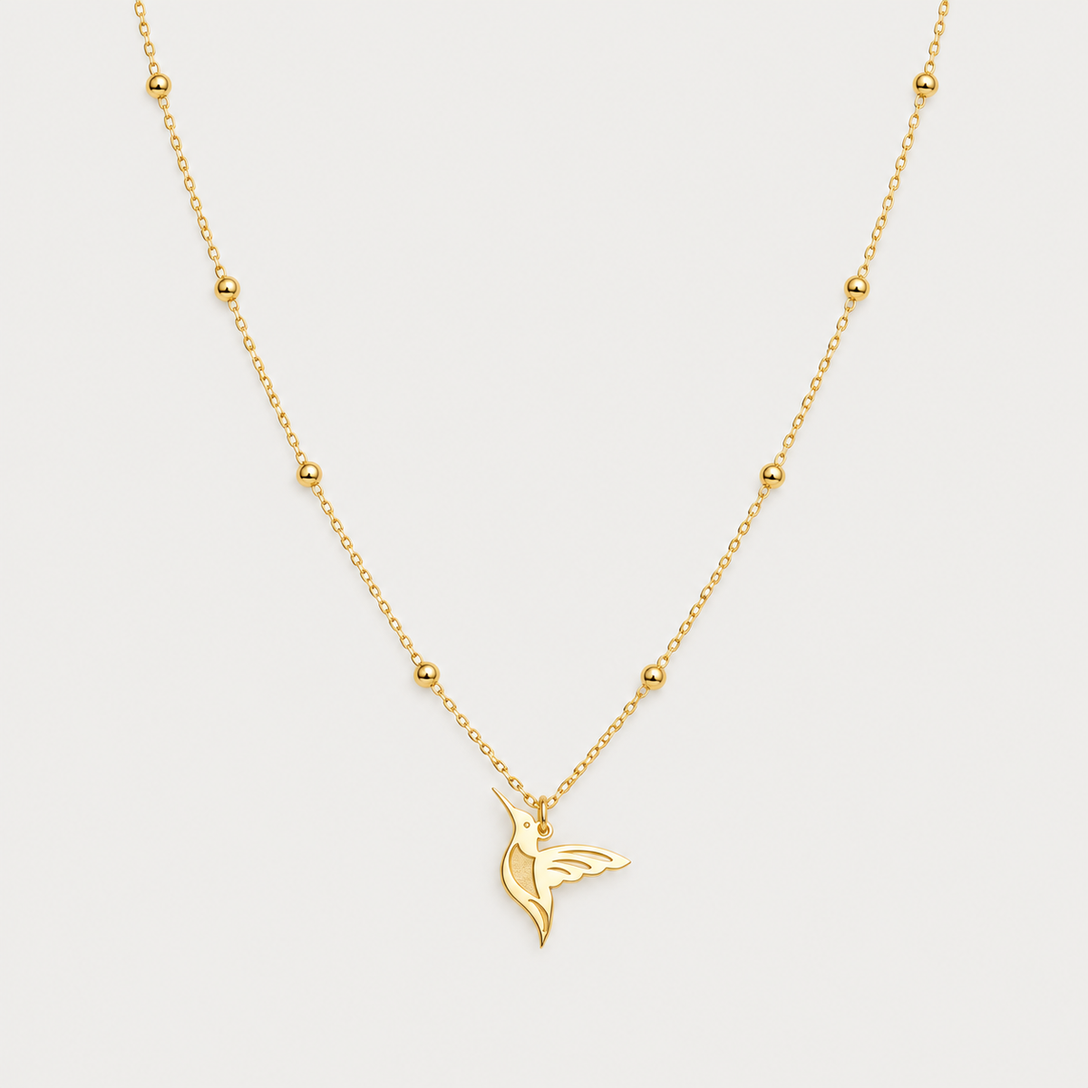 Gold hummingbird pendant on a beaded satellite chain, white background