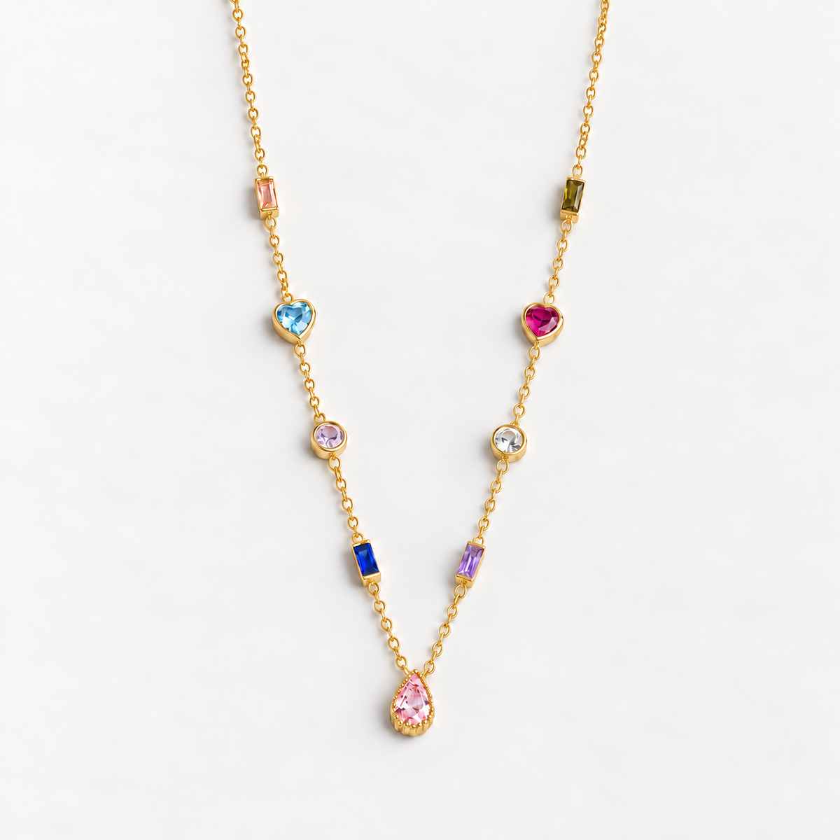Gold multiple birthstone necklace with nine colored stones and a pink teardrop pendant on a white background