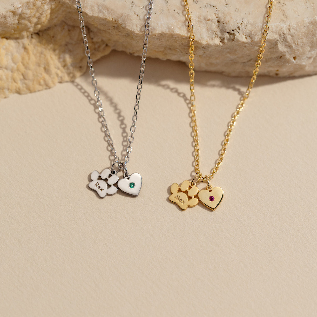 Two necklaces with heart-shaped pendants on a beige surface