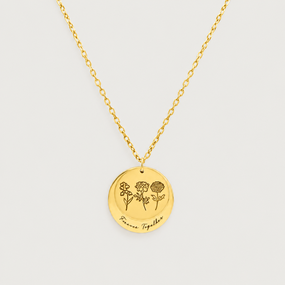 Gold double disc necklace engraved with three birth flowers and a script name, on a light background